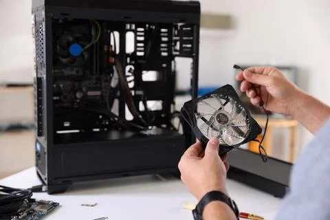Man installing fan into computer at white table, closeup Stock Photos