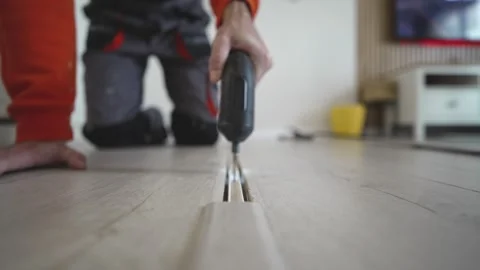 Man Installing Floor Transition Strip with Screwdriver at Home Stock Footage 329025066