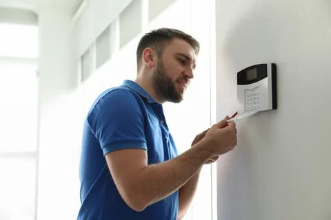 Man installing home security system on white wall in room Stock Photos