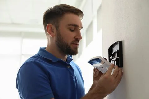 Man installing home security system on white wall in room Stock Photos