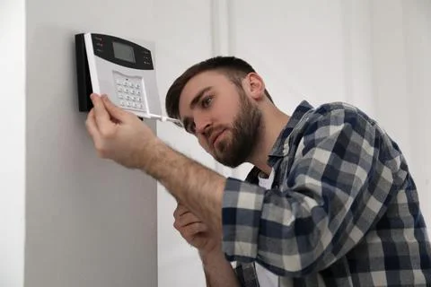 Man installing home security system on white wall in room Stock Photos