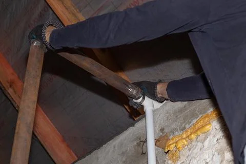 A man is installing an iron pipe for a solid fuel heating boiler in a private Stock Photos