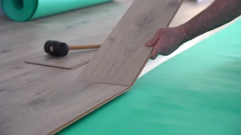 Man installing laminate flooring and connecting the laminate planks together. Stock Footage 148400742