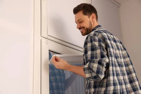 Man installing modern roller window blind indoors Stock Photos