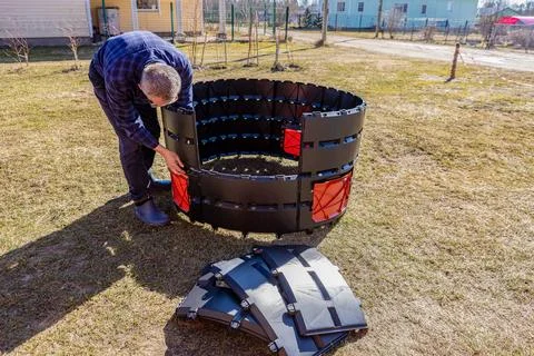 Man installing modular, stackable compost bin with a snap-together design. Fotos Stock