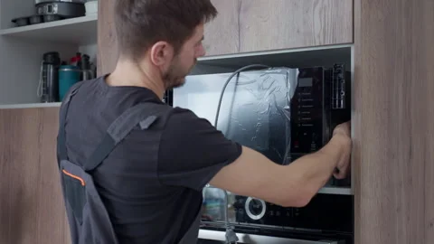 Man Installing New Microwave into Kitchen Cabinet Stock Footage 329479129