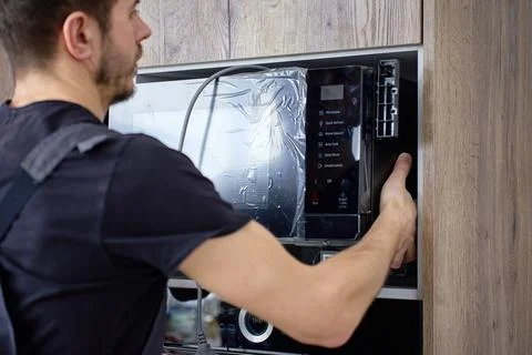 Man Installing New Microwave into Kitchen Cabinet Stock Photos