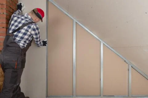 Man installing plasterboard sheet to wall for attic room construction Stock Photos
