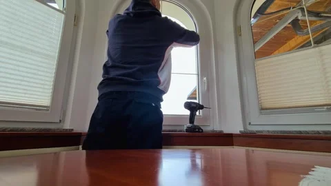 Man installing pleated window shade with drill at home DIY interior improvement Stock Footage 333803028