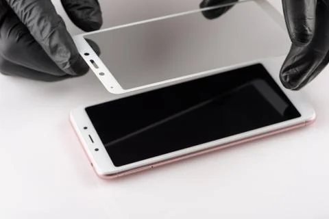 A man is installing a protective glass on the screen of a smartphone. Stock Photos