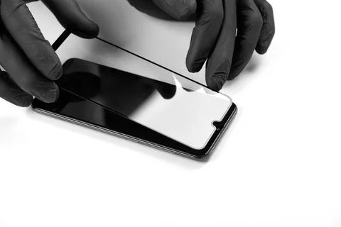 A man is installing a protective glass on the screen of a smartphone. Stock Photos