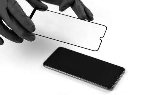 A man is installing a protective glass on the screen of a smartphone. Stock Photos