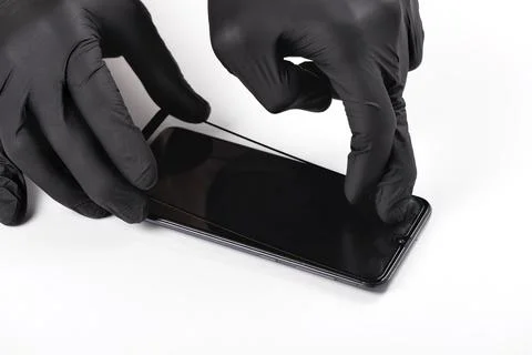 A man is installing a protective glass on the screen of a smartphone. Stock Photos