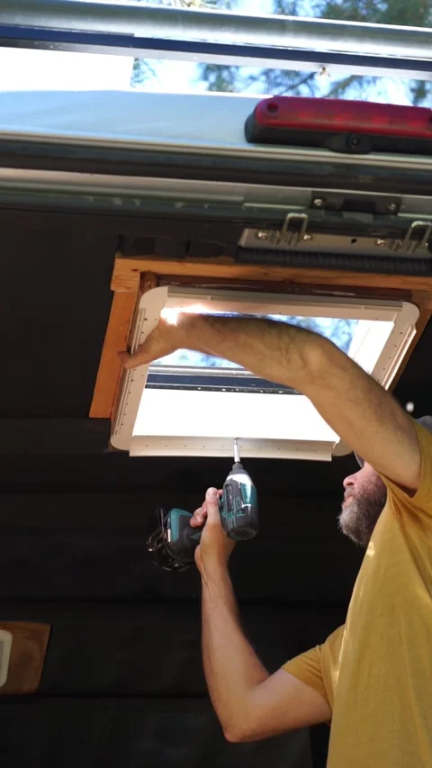 Man installing a skylight on a camper van. Caucasian man camperizing a van Stock Footage 274070705