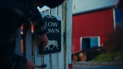 A Man Installing the "Slow Down" Animal Crossing Sign on a Fence - Close Up Stock Footage 297054249