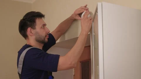 Man installing smoke detector on ceiling near doorway, professional technician Stock Footage 347875887