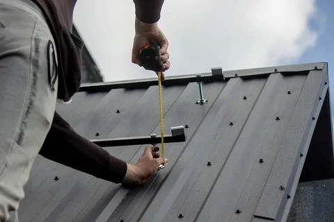 A man is installing solar panel mounts on the roof. Selective focus Stock Photos