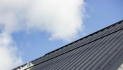 A man is installing solar panel mounts on the roof. Selective focus Stock Photos