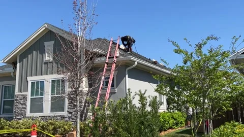 A man installing Tesla solar panels on the roof of a house. Stock Footage 178270259