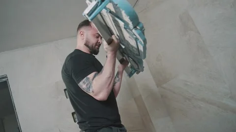 Man installing tile with precision and focus in a construction setting Video stock 307040264