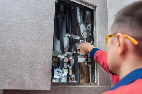 The man is installing the water supply system in the house and checking pipes by Stock Photos