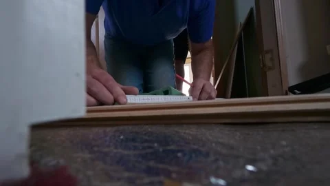 Man installing wooden laminate floor while kneeled down measuring and marking Stock Footage 341021693