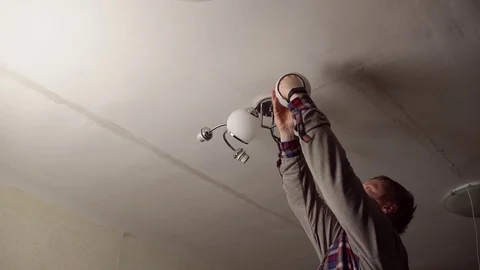 Man installs chandelier on the ceiling in room. Stock Footage 123660106