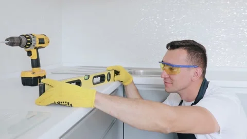 Man installs modern fitted kitchen. Master check the level of kitchen furniture Stock Footage 130452486