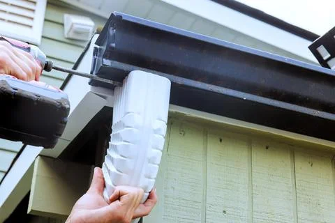 Man installs new gutter section on house Fotos de archivo