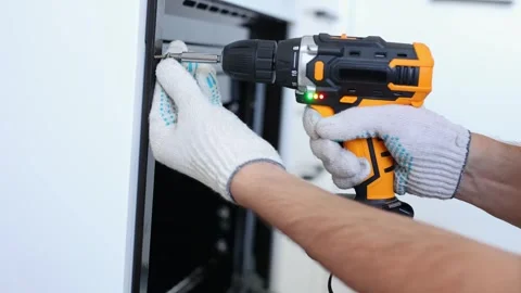 Man installs the oven after assembling the kitchen and screws the bolts Stock Footage 266888380