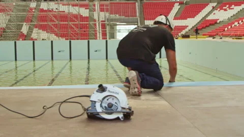 Man installs overflow grate under swimming pool edge Stock Footage 234899192