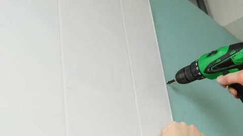 Man installs screw using screwdriver securing plasterboard Stock Footage 304407726