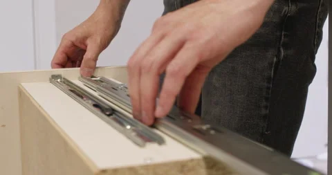 Man installs sliding system on drawer during furniture assembly Video stock 323967495