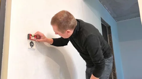 Man installs a wall switch in a room during home renovation work in late afterno Stock-Footage 326698324