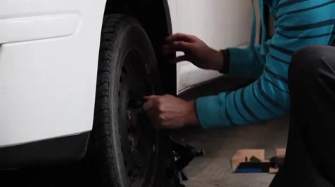 Man installs wheel on car Stock Footage 46090684