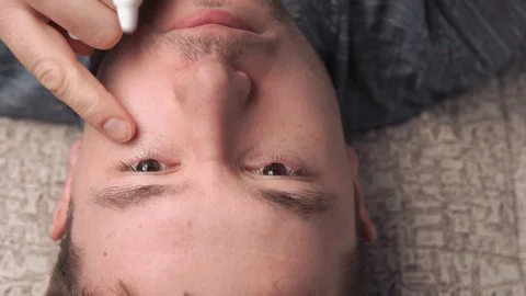 Man instilling eye drops while lying Stock Footage 103497527