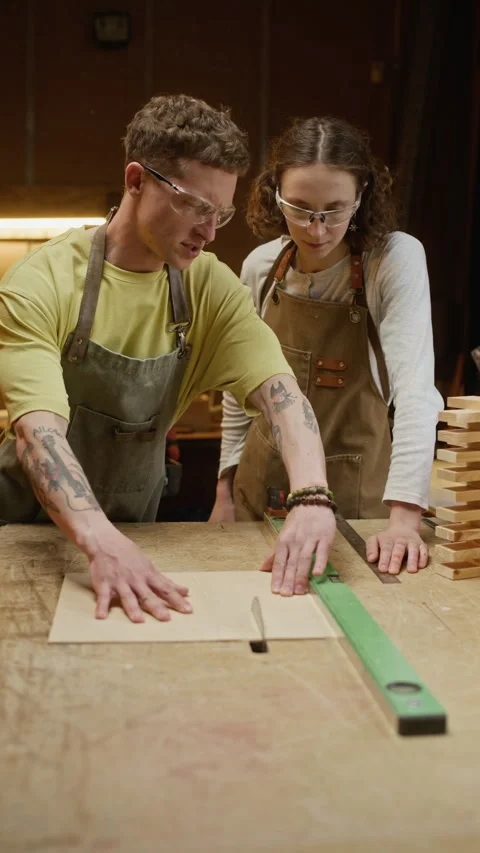 Man Instructing Woman on Using Table Saw in Carpentry Workshop Stock Footage 340403221