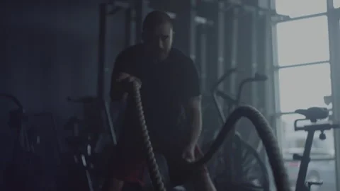 Man intensively trains with ropes and finishes his workout breathing hard Stock Footage 312707572