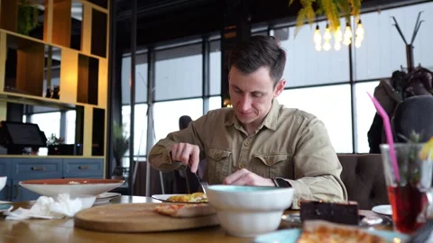Man intently eats food using fork with thoughtful gaze Stock Footage 308441092