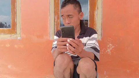 A man intently using his phone outside his home. Stock Footage 317933808