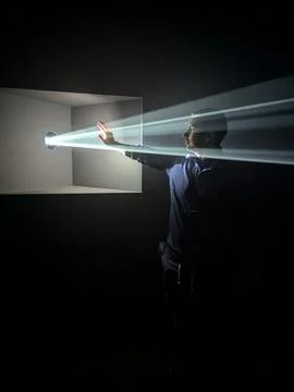 Man Interacting With Beams of Light in a Dark Room, Bilbao, 2 August 2024. Foto stock