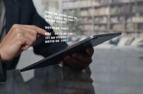 Man Interacting with Tablet Displaying Binary Code in Modern Office 스톡 사진