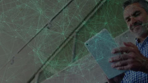 Man interacting with tablet indoors, displaying animated green network nodes for Stock Footage 307445078