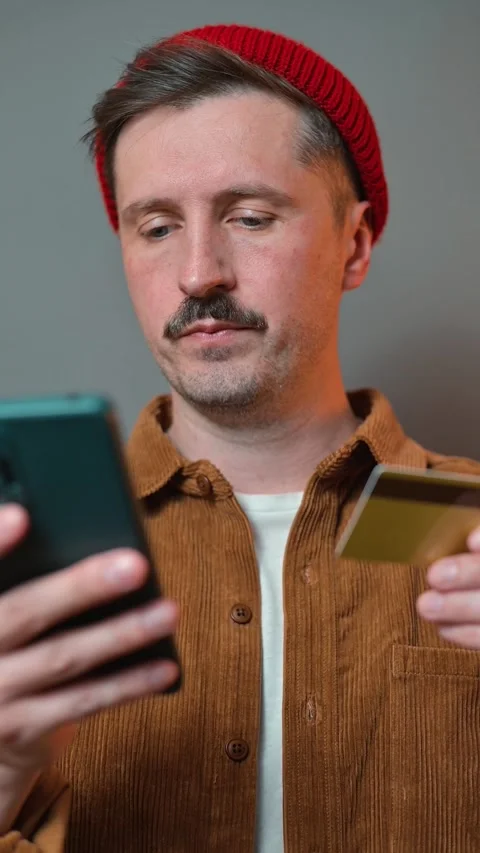 A man interacts with his smartphone while holding a credit card, showing signs Video stock 337643100