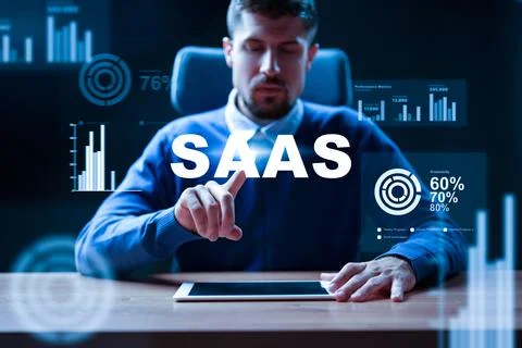 Man interacts with SaaS interface on tablet in office setting during evening Stock Photos