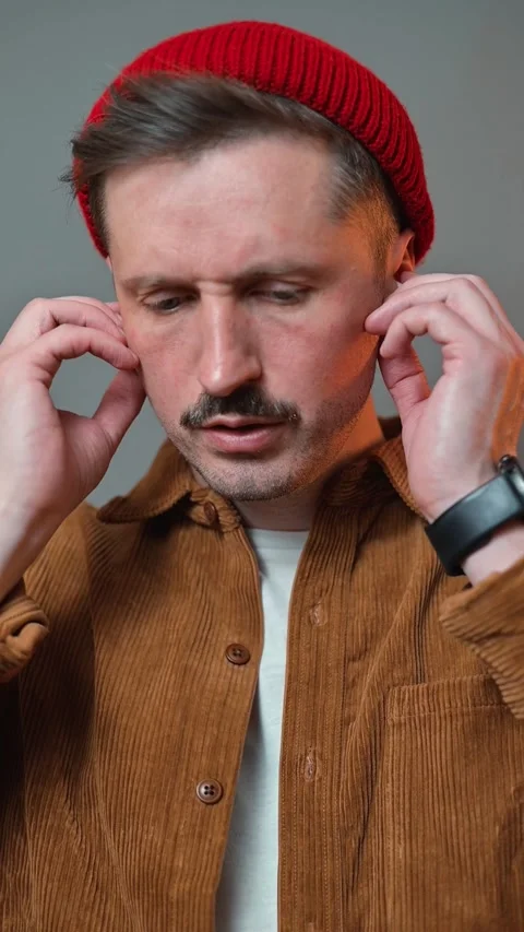 A man interacts with wireless headphones, demonstrating a broken, non-functional Stockbeeldmateriaal 337643096