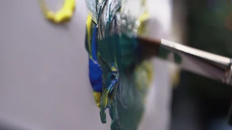 Man interferes with the color of the brush to get a blue color for the picture Stock Footage 124867317