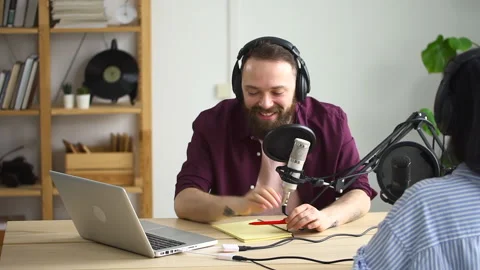 Man interviewing guest in a studio for a podcast Spbd. Happy host smile laugh Stock Footage 154594552