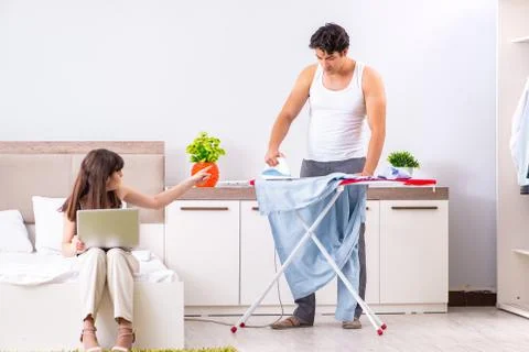 Man ironing, his lazy wife sitting Stock Photos