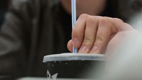 A man irritably knocks a straw on the bottom of a glass with a drink, close-up 스톡 동영상 237403244